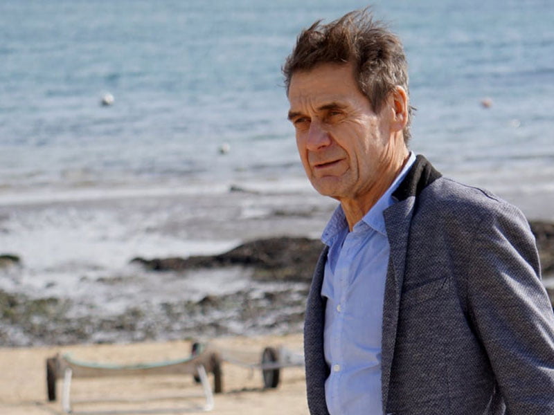 Windswept old man with beach in background