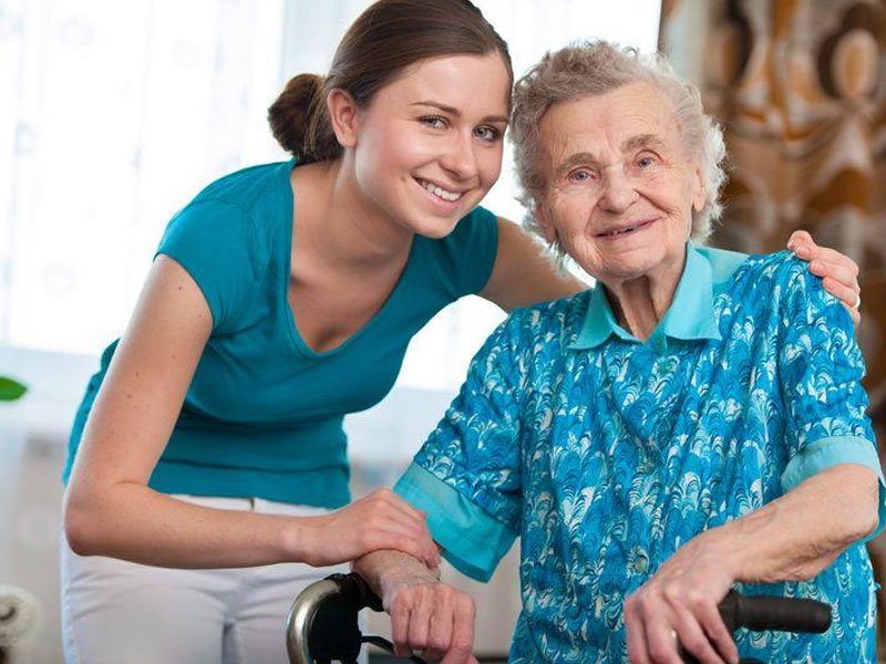 Young woman assisting an old woman on a walking aid