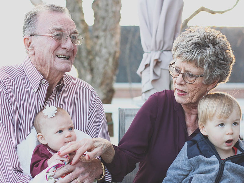 Happy elderly couple holding grand children