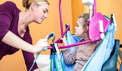 Disabled child being helped into a hoist